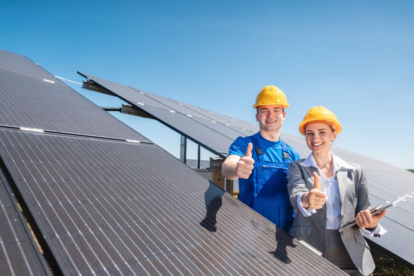 Worker and investor in solar power plant pointing at the sun